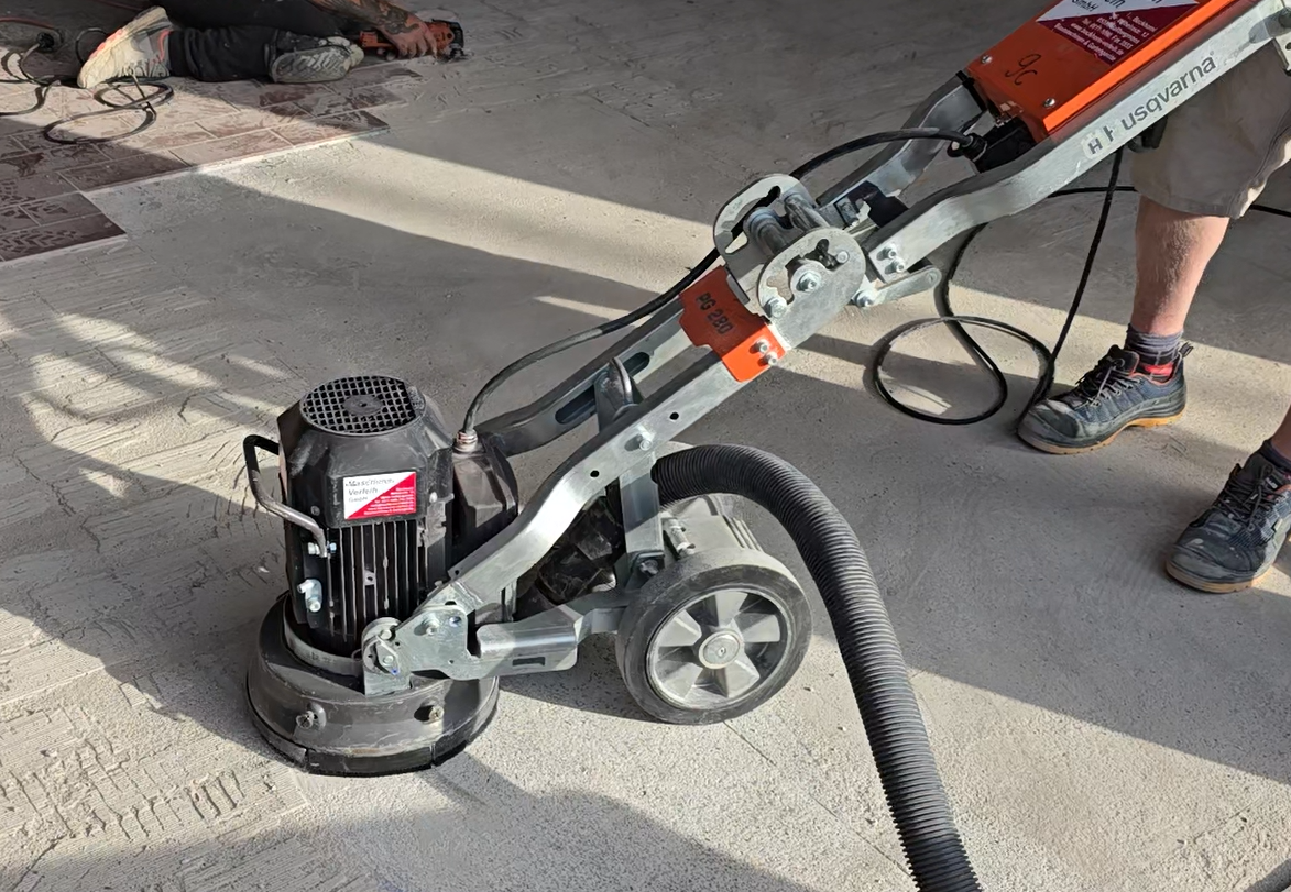 Die Bodenschleifmaschine schleift Fliesenkleber vom Estrich ab.
