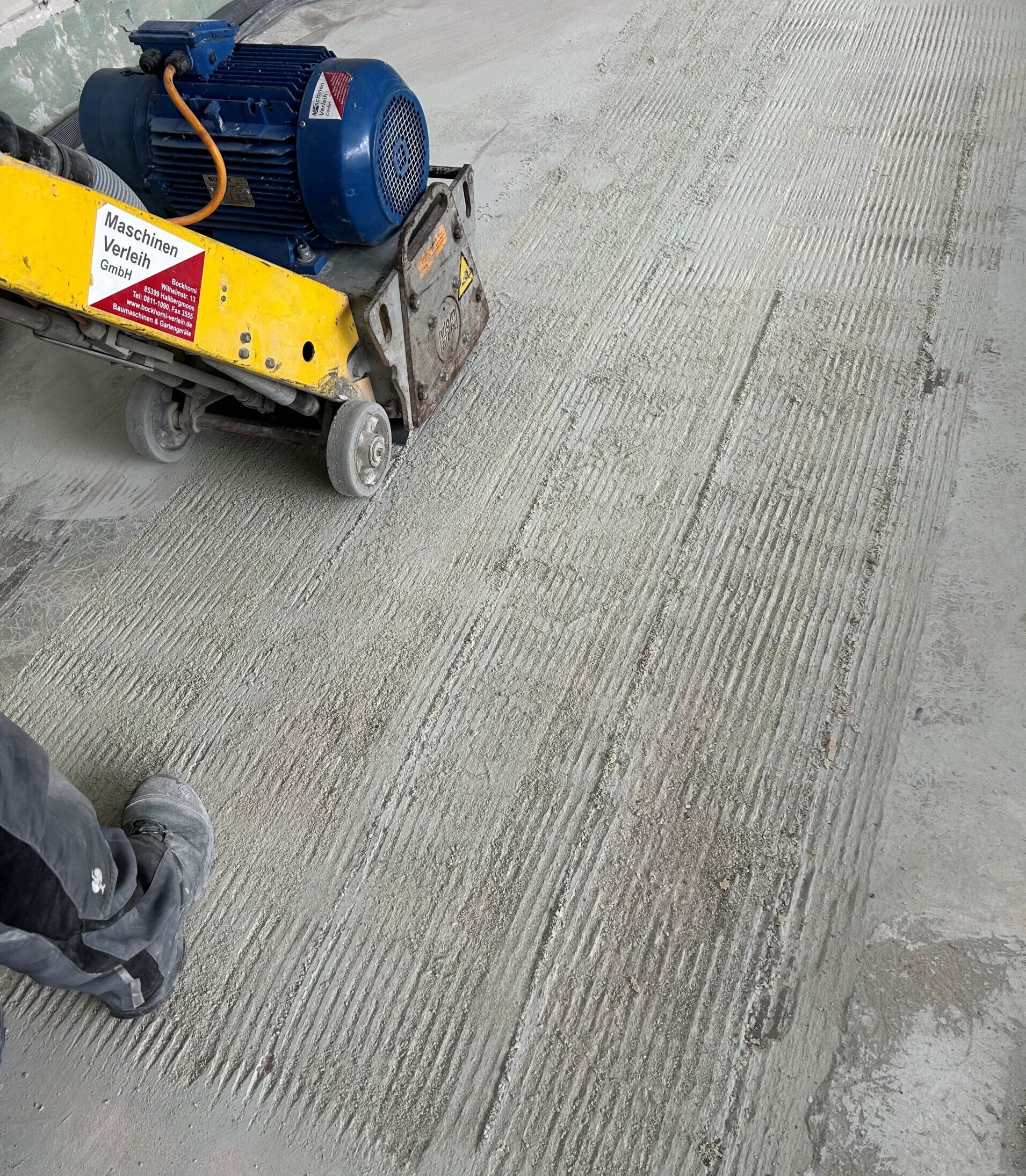 Die Betonfräse fräst Beton am Boden ab.
