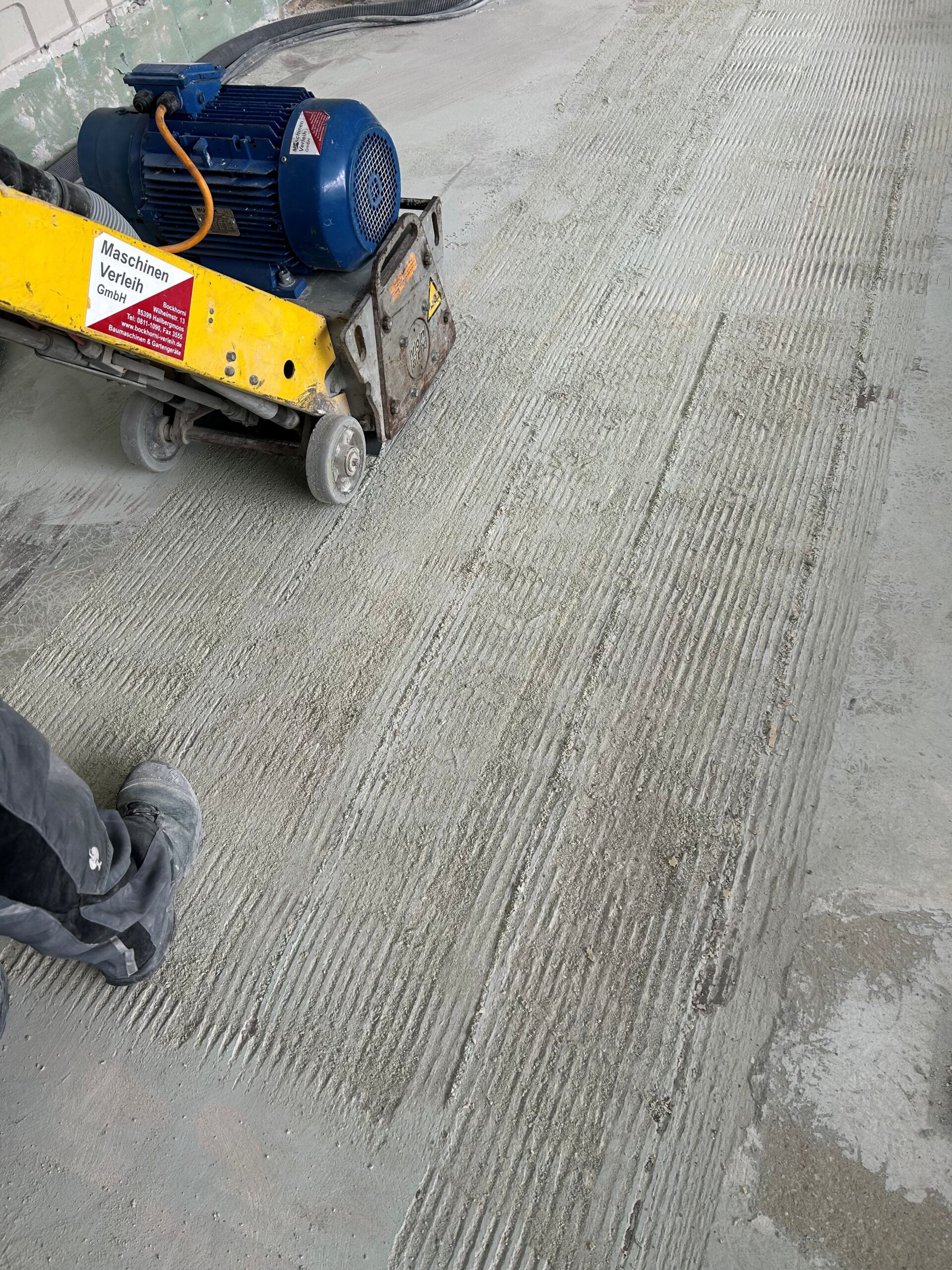 Die Betonfräse fräst Beton am Boden ab.