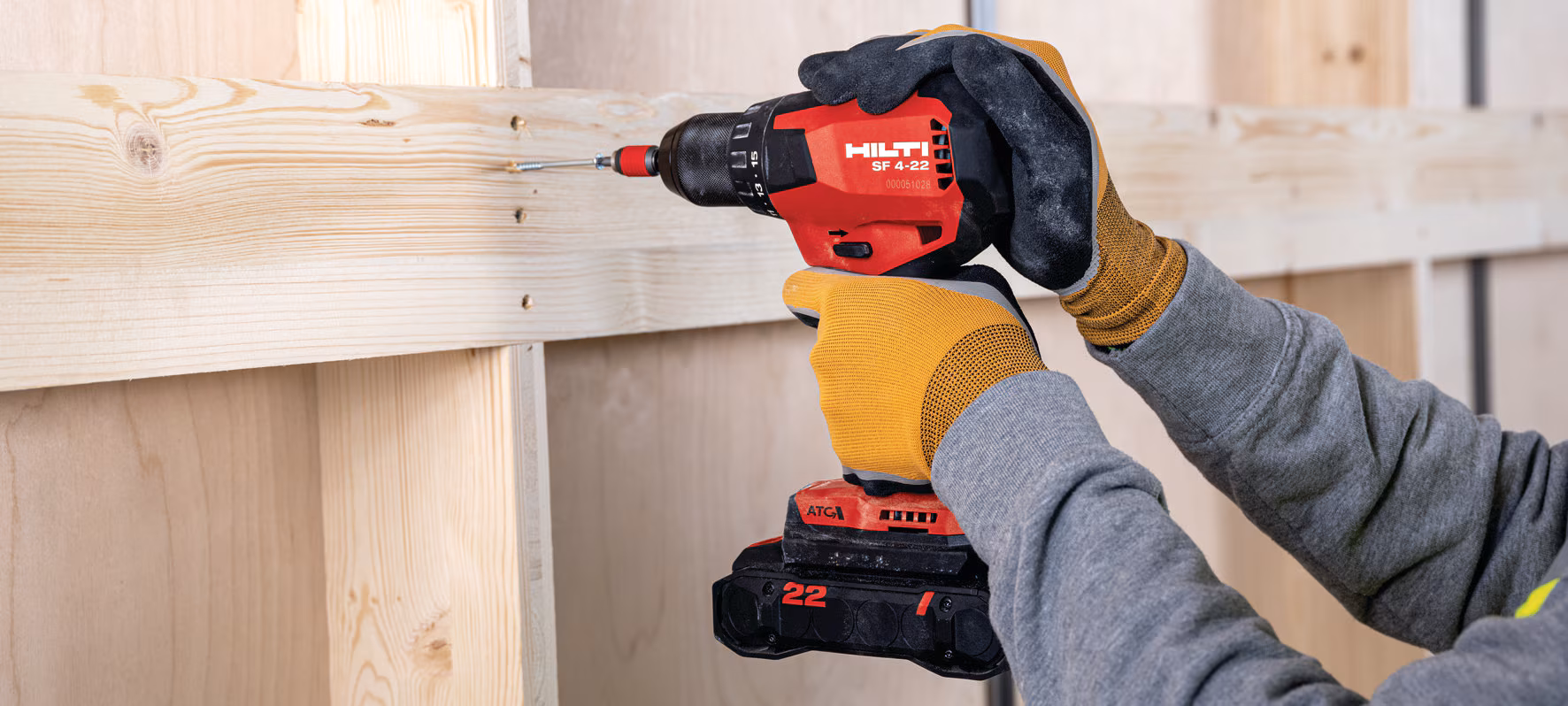 Der Akkubohrer schraubt eine Schraube in eine Holzwand.