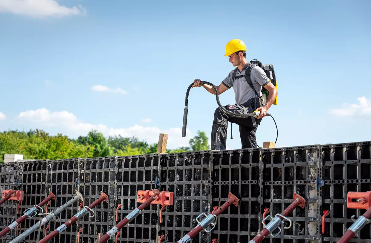 Der Bediener steht auf einer Schalung mit dem Akku-Innenrüttler in der Hand